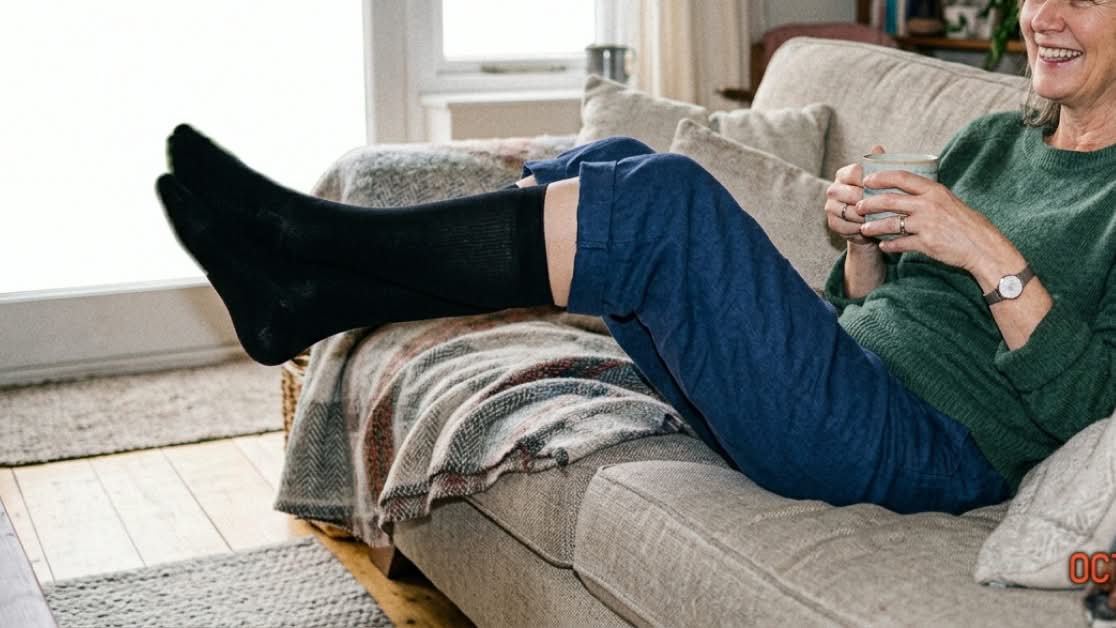 Person on a sofa with feet up, wearing dark socks.